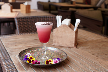 Red cocktail with froth, flowers and chocolate in bar