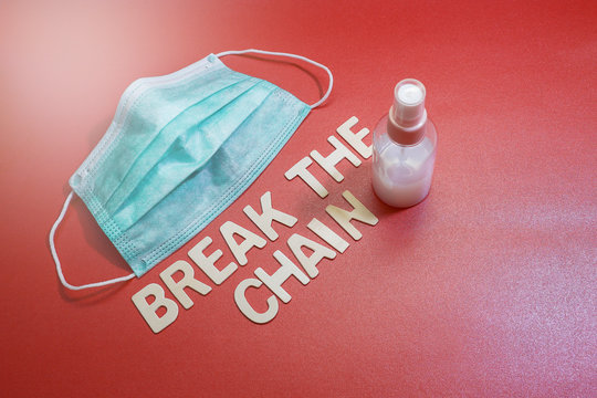 A face mask with a bottle of hand sanitizer with wood lettering on a red background.  Message on virus spread