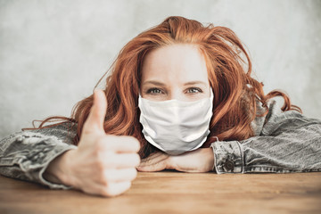 Young, attractive, red-haired woman with curly hair wearing a breathing mask in the pandemic