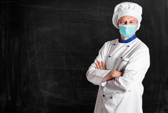 Masked chef in front of an empty blackboard, coronavirus restaurant concept