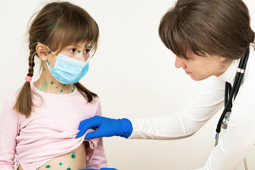 Doctor examining child girl covered with green rashes on face and stomach ill with chickenpox,...