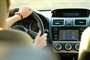 Close up view of woman hands holding steering wheel driving a car on city street on sunny day.