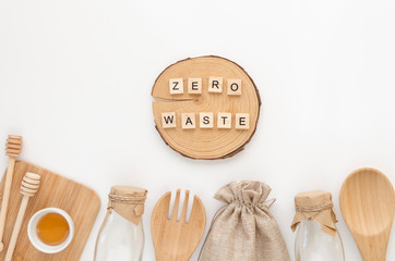 ZERO WASTE phrase made of wooden letter cubes with set of eco friendly wooden bamboo cutlery on a white table. Flat lay, top view
