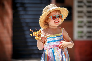 Cute happy curly toddler girl walking in city