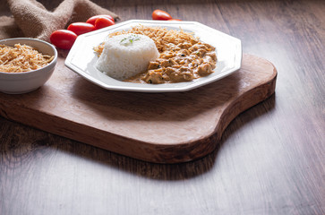 Food plate with meat stroganoff with rice and french fries. Wood background.