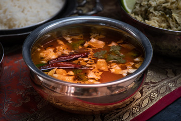 Tomato rasam and papad in traditional Indian serving bowl