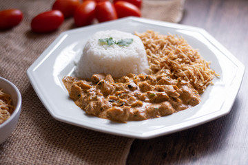 Food plate with meat stroganoff with rice and french fries. Wood background.