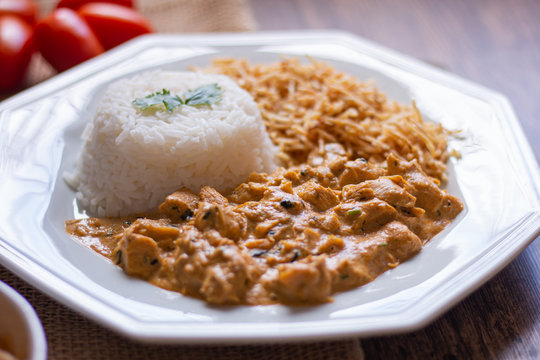 Food plate with meat stroganoff with rice and french fries. Wood background.