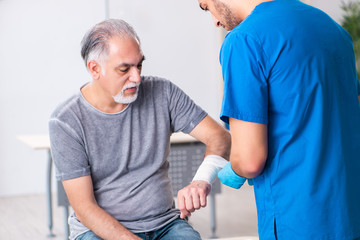 Obraz premium Young male doctor and old patient in first aid concept