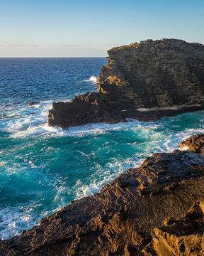 Turquoise seawater breaking on a rock cliff in Hawai