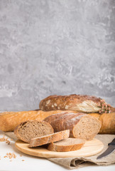 Sliced bread with different kinds of fresh baked bread on a gray concrete background. side view, selective focus.