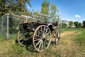Fototapeta na wymiar DALLIKON, SWITZERLAND - APRIL 18, 2020: An old wooden vintage carriage from old times stands in front of a farm by the road