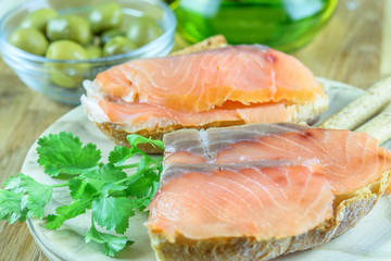 Sandwiches with red fish salmon on the wooden plate closeup. Light fast food concept.