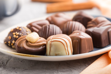 Different chocolate candies and a cup of coffee on a gray concrete background. side view, selective focus.