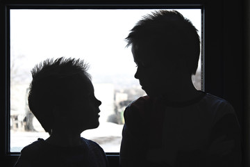 Silhouettes of little boys who look at each other.
