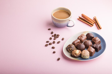 Different chocolate candies and a cup of coffee on a pink pastel background. side view, copy space.
