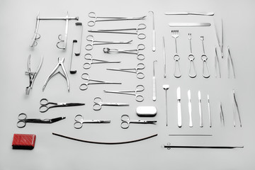 Medical instruments used for surgical operations, laid out on a gray background