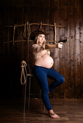 pregnant girl cowboy sitting on a chair with a gun. country style. lasso.