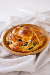 Delicious homemade pastries with raisins.  Wicker bun on a round wooden plate.  Baking on a light background.