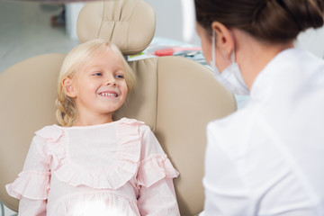 Fototapeta premium Image of a little female child having her teeth checked by a doctor