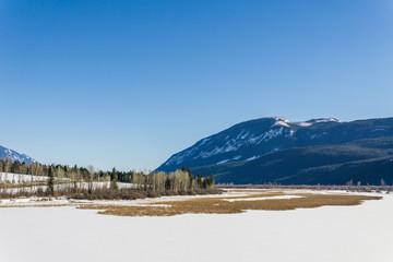 Obraz premium spring valley in snow near high mountain with blue clear sky.