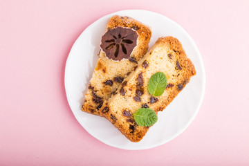 Homemade cake with raisins and dried persimmon on a pink pastel background. Top view.