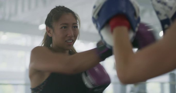 Girl boxer punching pads in ring