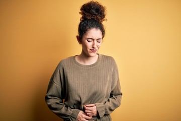 Obraz premium Young beautiful brunette woman with curly hair and piercing wearing casual dress with hand on stomach because indigestion, painful illness feeling unwell. Ache concept.