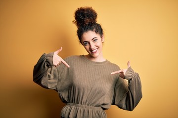 Young beautiful brunette woman with curly hair and piercing wearing casual dress looking confident...