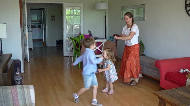 Young mother and two children dancing and having fun at home during coronavirus quarantine
