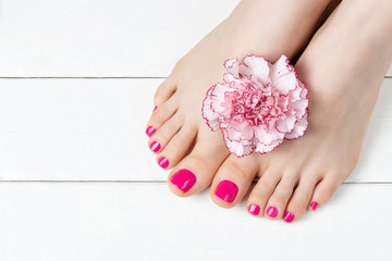 Obraz na płótnie Canvas Pink pedicure with a flower on white wooden background, top view, copy space