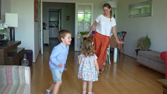 Young mother and two children dancing and having fun at home during coronavirus quarantine