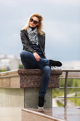 Happy young fashion woman in leather jacket and sunglasses