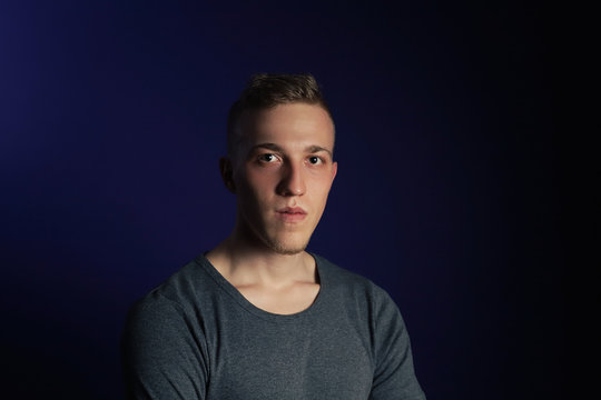 Young Caucasian Blonde Man In Grey T Shirt On Dark Purple Background