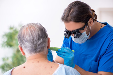 Old man visiting young male doctor dermatologist