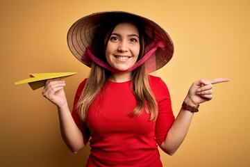 Tourist woman wearing traditional asian rice paddy straw hat holding paper plane for a trip very...