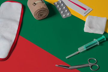 Lithuania flag with first aid medical kit on wooden table background. National healthcare system concept, medical theme.