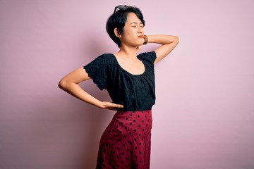 Young beautiful asian girl wearing casual dress standing over isolated pink background Suffering of neck ache injury, touching neck with hand, muscular pain