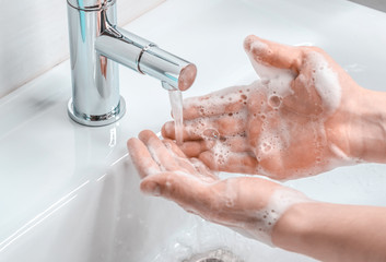 Hand washing with soapy water in the bathroom. A young guy washes his hands with soap. The fight against coronavirus.