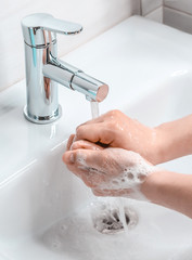 Hand washing with soapy water in the bathroom. A young guy washes his hands with soap. The fight...