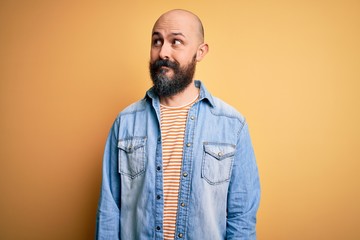 Obraz premium Handsome bald man with beard wearing casual denim jacket and striped t-shirt smiling looking to the side and staring away thinking.