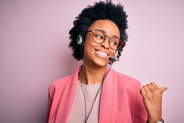 Young African American call center operator woman with curly hair using headset smiling with happy...
