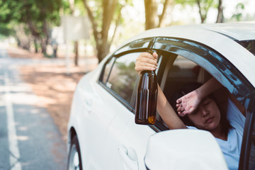Drunk asian women drinking alcohol while driving car on road,Woman drive her car with a bottle of...