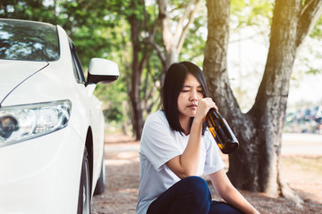 Drunk asian woman drinking alcohol while driving car on road,Women drive her car with a bottle of beer,Dangerous driving concept