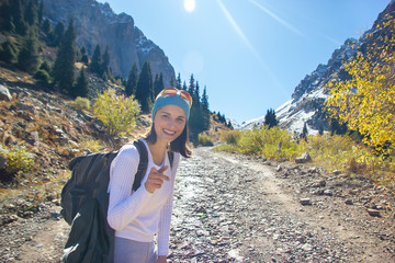 A young happy woman smiles into the camera. Mountains in the background.