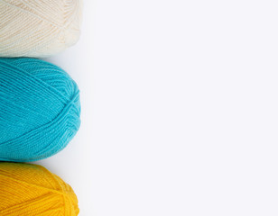 three skeins of woolen threads on a white background, white, yellow and blue on the left side, horizontal position copy space on right side 