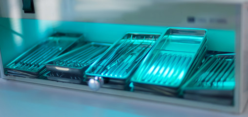 Sterilization of instrument with ultraviolet lamp in dental clinic. Closeup different medical ...