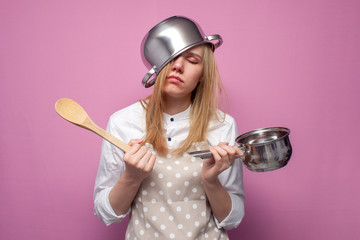 tired girl cook in kitchen clothes with a pan on her head sleeps on a colored background, hard work...