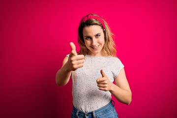 Young beautiful blonde woman wearing casual t-shirt standing over isolated pink background pointing fingers to camera with happy and funny face. Good energy and vibes.