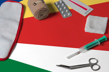 Seychelles flag with first aid medical kit on wooden table background. National healthcare system concept, medical theme.